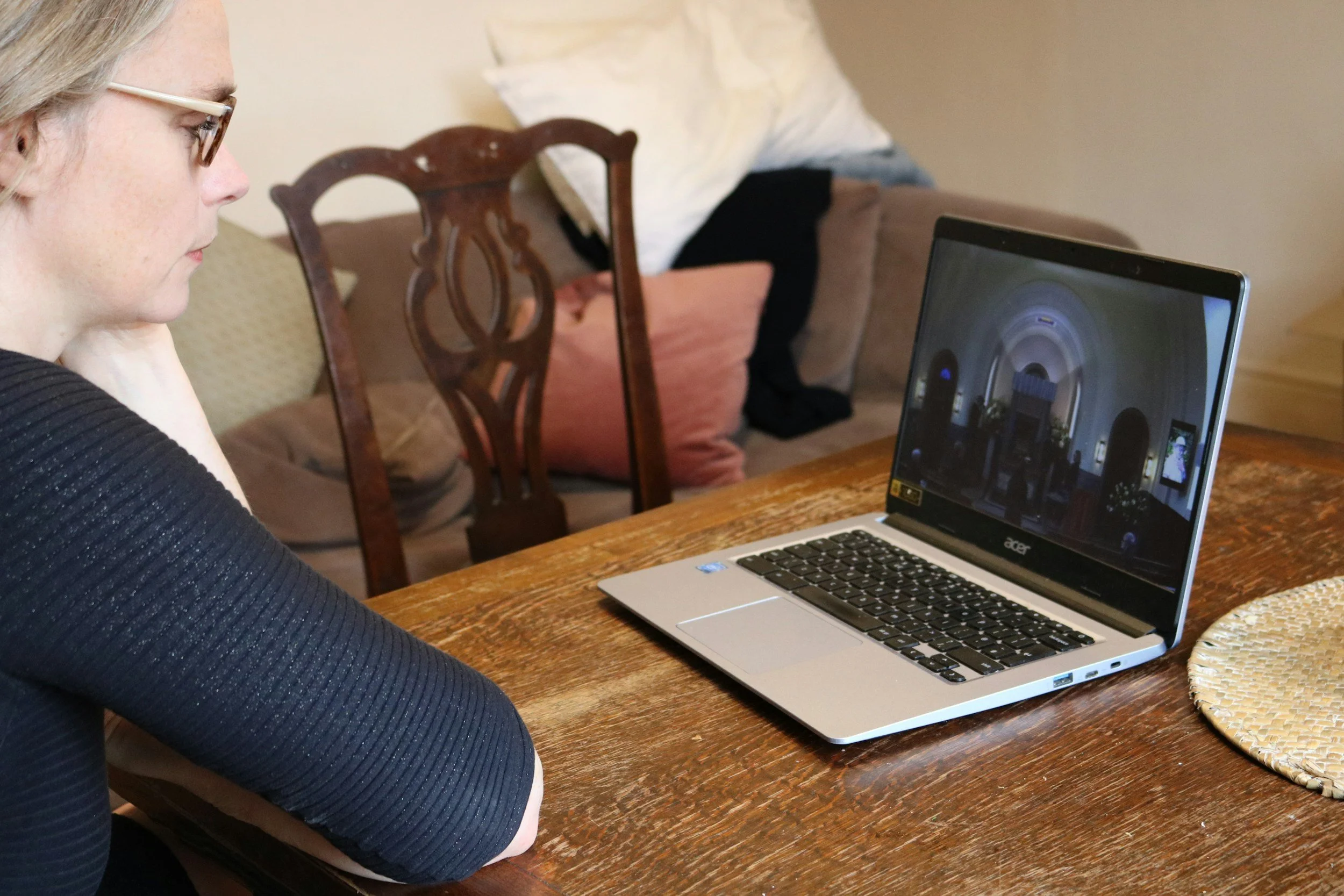 Woman at home watching a funeral service live stream on a laptop